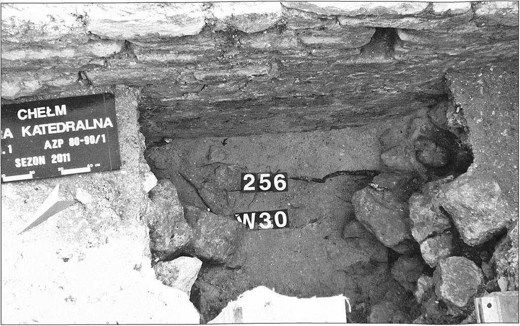 The external face o f the masonry wall and adjoining layers of destroyed remains are visible. No. 256 marks the level of lime screed.