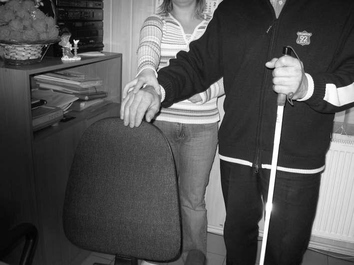Wskazując niewidomemu krzesło połóż dłoń tej ręki którą trzyma Cię niewidomy, na oparciu. Jeśli niewidomy porusza się z psem, wystarczą zazwyczaj wskazówki słowne.