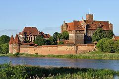 królów Polski. Malbork Castle, surrounded by a moat, was built in several stages by the Teutonic Knights.