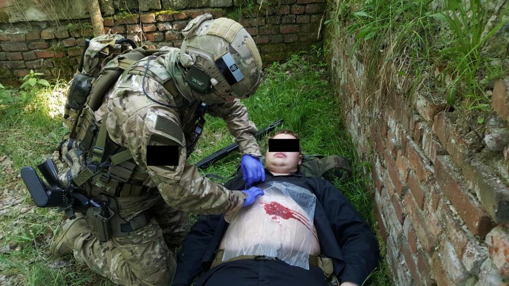 Zdjęcie 23. Medyk stosujący lateksową folię opatrunku OLAES na ranie brzucha. (zdj.