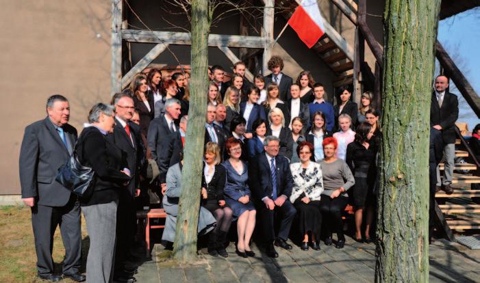 Fotografi de grup a bursierilor şi membrilor AC Echo Pyzdr cu Preşedintele Poloniei Bronisław Komorowski în faţa sediului Asociaţiei Culturale Echo Pyzdr, martie 2012.