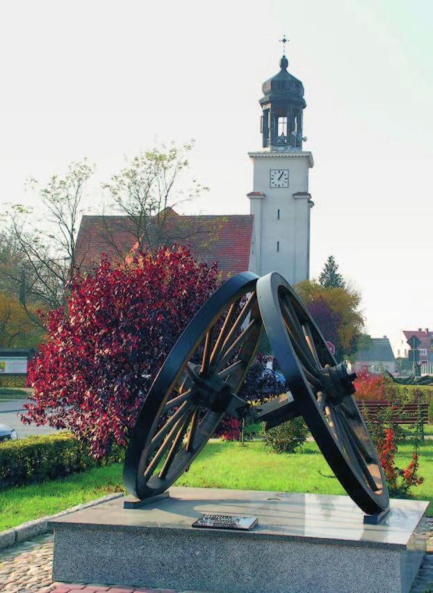 W centrum Rynku w 2005 roku postawiono obelisk przedstawiający koła ze złamaną osią, według legendy źródło nazwy wsi, dziś herb miejscowości.