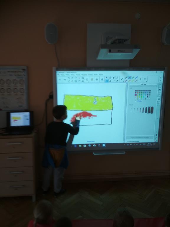 Starsze grupy rysowały na tablicy multimedialnej kontury flagi Warszawy wypełniając kolorami (żółto czerwoną), a inne grupy wyklejały flagę plasteliną.
