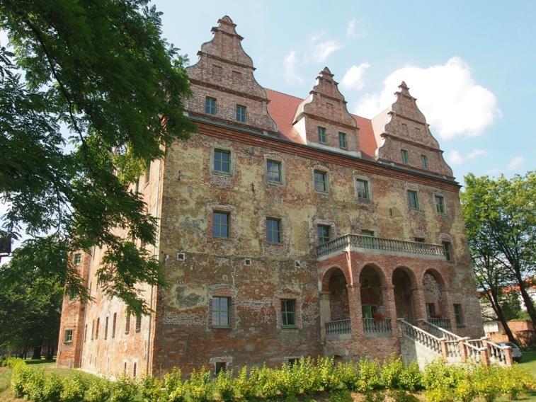 W narożach zachodniej, frontowej elewacji znajdują się ośmioboczne baszty nakryte hełmami. Neorenesansowy portal posiada tablicę z inskrypcją dot.