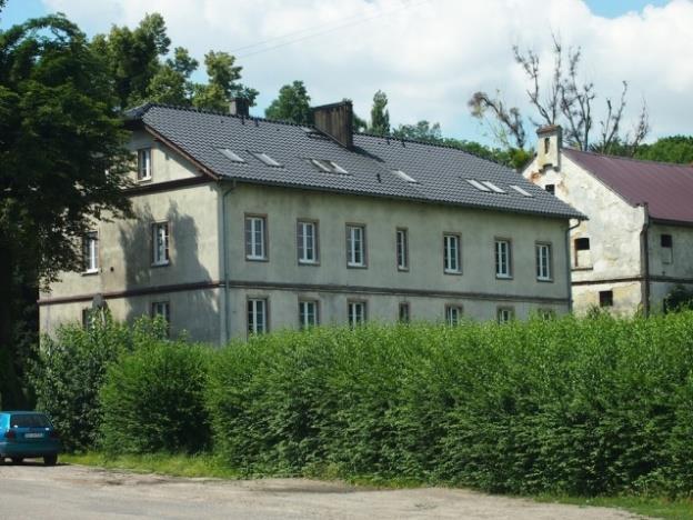 Założony na rzucie wydłużonego prostokąta, z sienią na osi środkowej, dwukondygnacyjny, częściowo podpiwniczony, z poddaszem. Murowany z cegły, otynkowany.