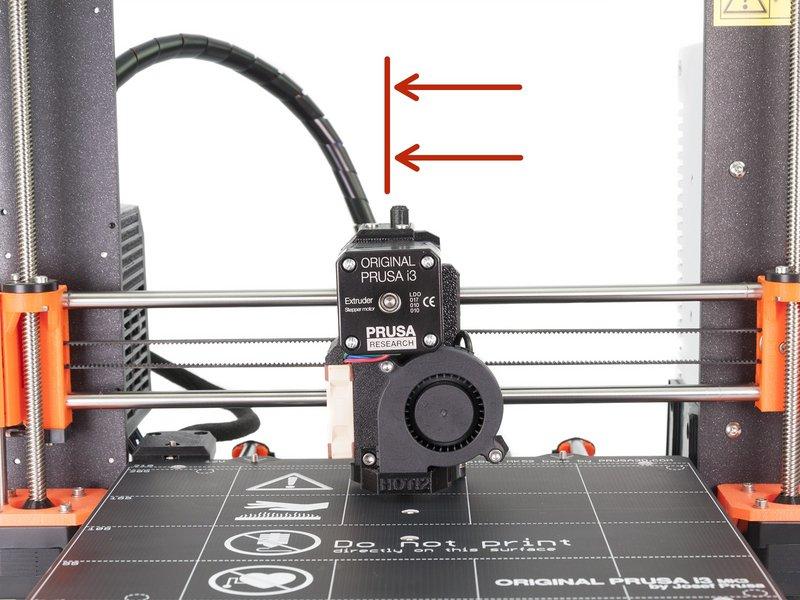 Step 3 Ustawienie sondy P.I.N.D.A. (część 3) Przesuń ekstruder do środka osi X. Wyjmij opaskę zaciskową z opakowania i umieść ją pod sodą P.I.N.D.A. Użyj jej środkowej części, a nie końcówki.