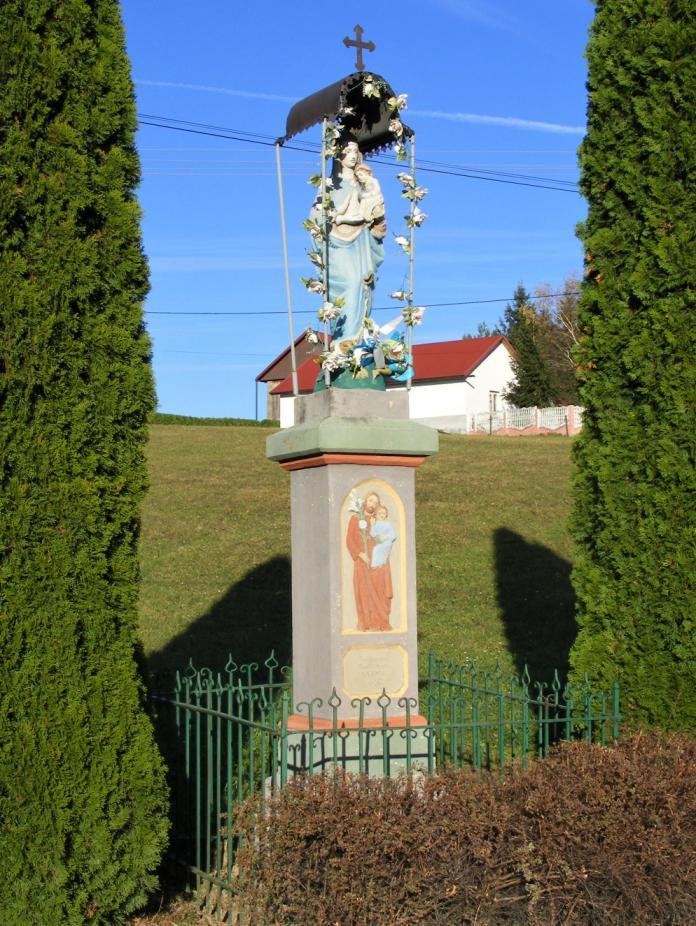 Obok domu Krystyny i Adama Bąków na betonowym postumencie stoi figura Matki Bożej Niepokalanej (odlew).