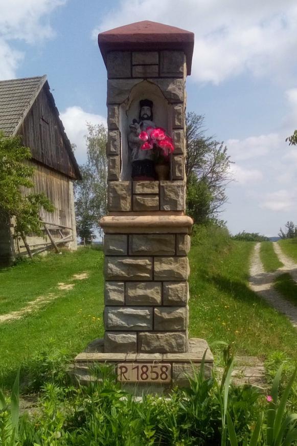 Historia kapliczki: Joanna Wrona w wieku ok. 40 lat ciężko zachorowała. Nie mogła jeść ani spać. Jej mąż- Adam Wrona nie wiedział co robić. Postanowił więc poprosić o radę Matkę Boską.