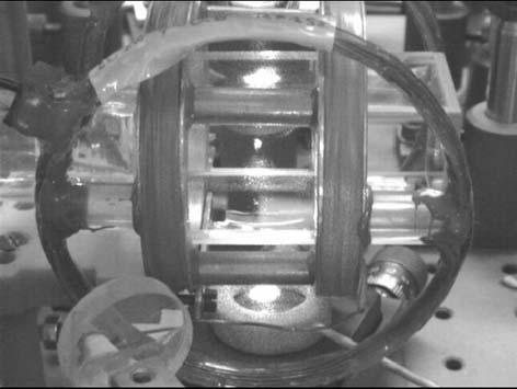 Rys..13 Zdjęcie komórki próżniowej pułapki magneto-optycznej. W centrum widać fluorescencję chmury spułapkowanych atomów. Rys.