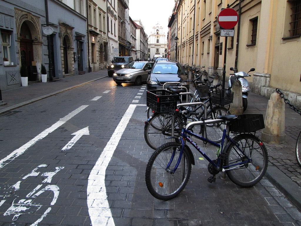 Fot. 16. Stojaki rowerowe zlokalizowane w jezdni w obrębie skrzyżowania. Poprawia to widoczność wzajemną i eliminuje ryzyko nieprawidłowego parkowania. Ul. św. Jana, Kraków.