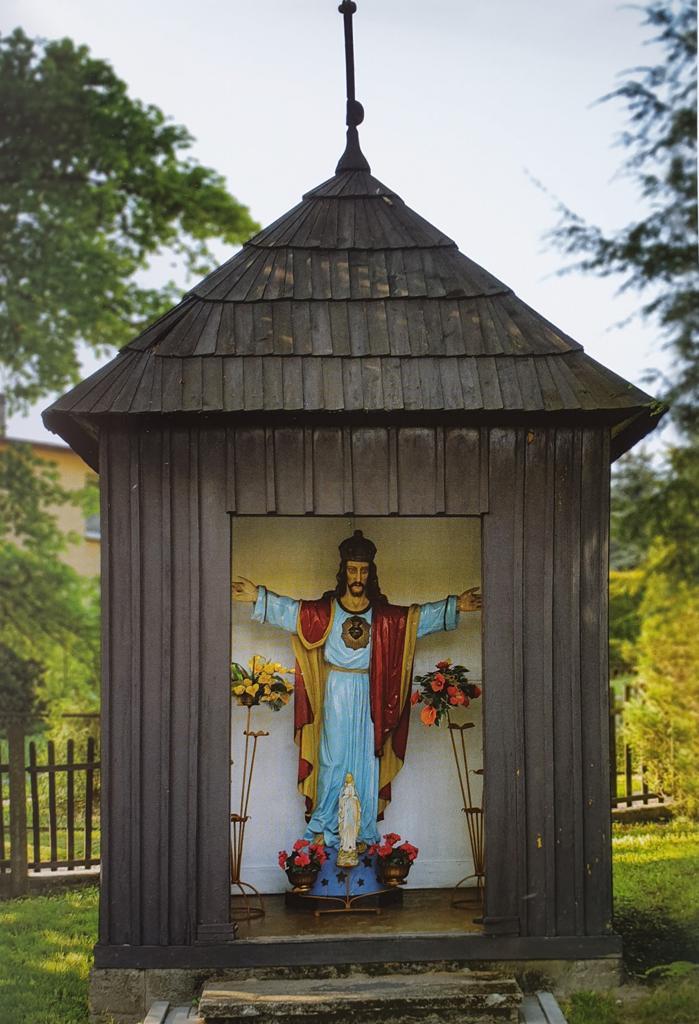 Przechodząc przez bramę główną do kościoła w Łaziskach,mijamy usytuowaną po lewej stronie chodnika drewnianą kapliczkę, w której w środku ustawiona jest figura Chrystusa Króla.