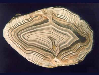 Zadanie 22. Minerał przedstawiony na rysunku to wielobarwna, wstęgowa odmiana chalcedonu. Często występuje w geodach. Jest to A. opal. B. agat. C. kwarc. D. cytryn. Zadanie 23.
