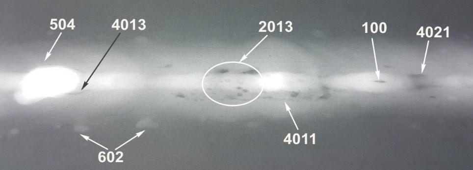 Radiogram złącza wzdłużnego spoiny jednostronnej z wykrytymi niezgodnościami: 100 pęknięcie, 2013 gniazdo pęcherzy, 4011 przyklejenie brzegowe, 4013 przyklejenie graniowe, 4021 brak przetopu, 504