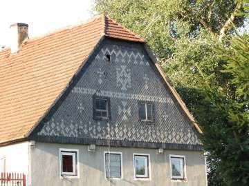 podwójna łuskę, w połaci dachowej w elewacji frontowej obecne wole oko, szczyty budynku obłożony